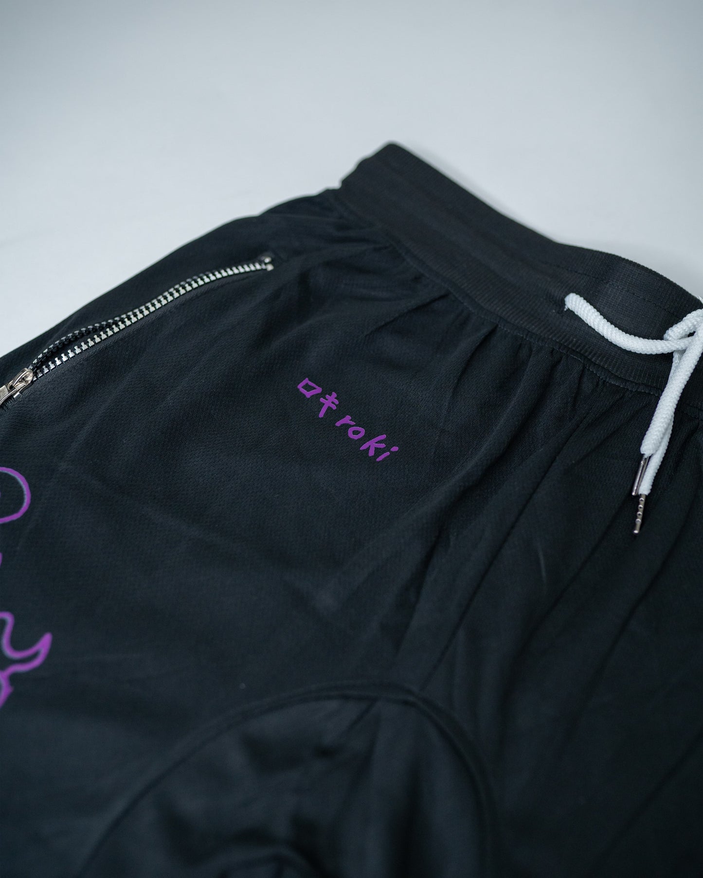 Close-up of black Roki Awakened gym shorts featuring purple accents and Roki logo