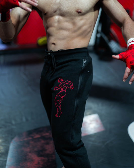 Gym close-up of Grappler Joggers worn by fighter showing red embroidered baki the grappler inspired design and zip pocket detailing