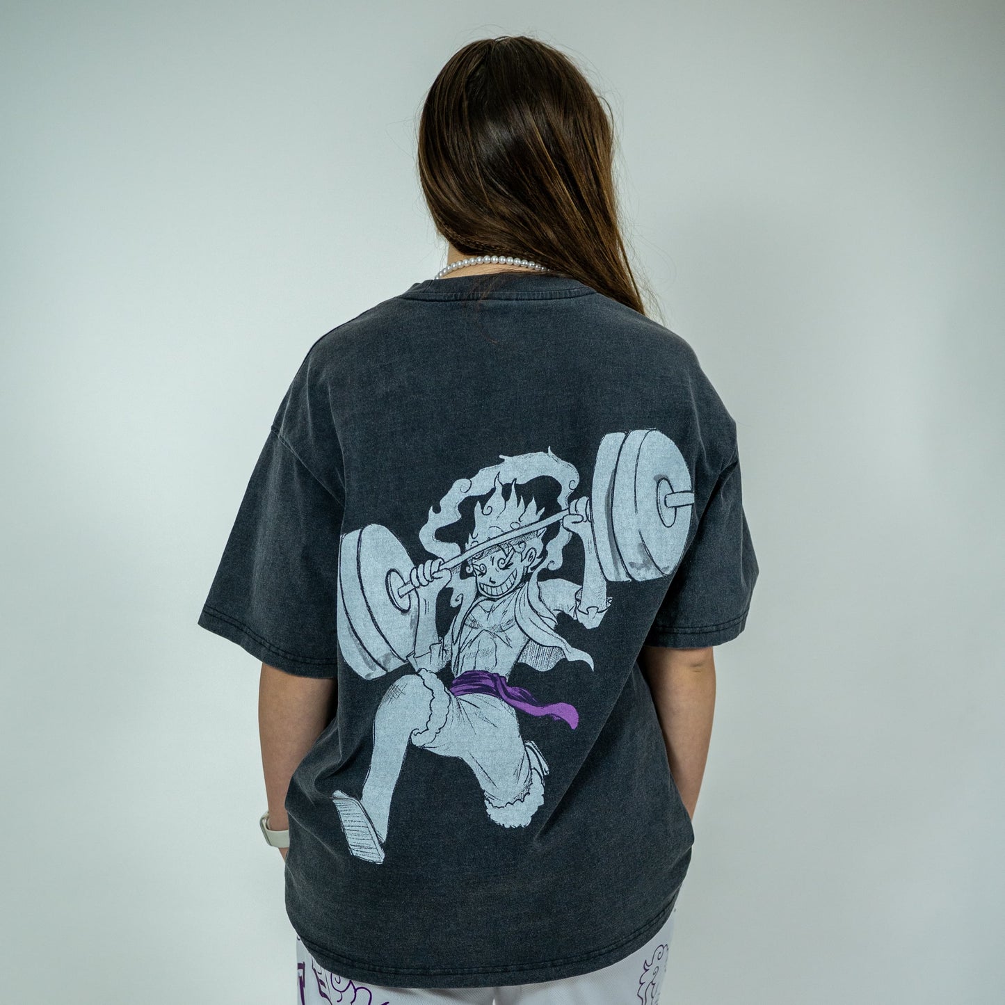 Back view of a model wearing a black Roki muki muki oversized t-shirt featuring a manga-inspired design