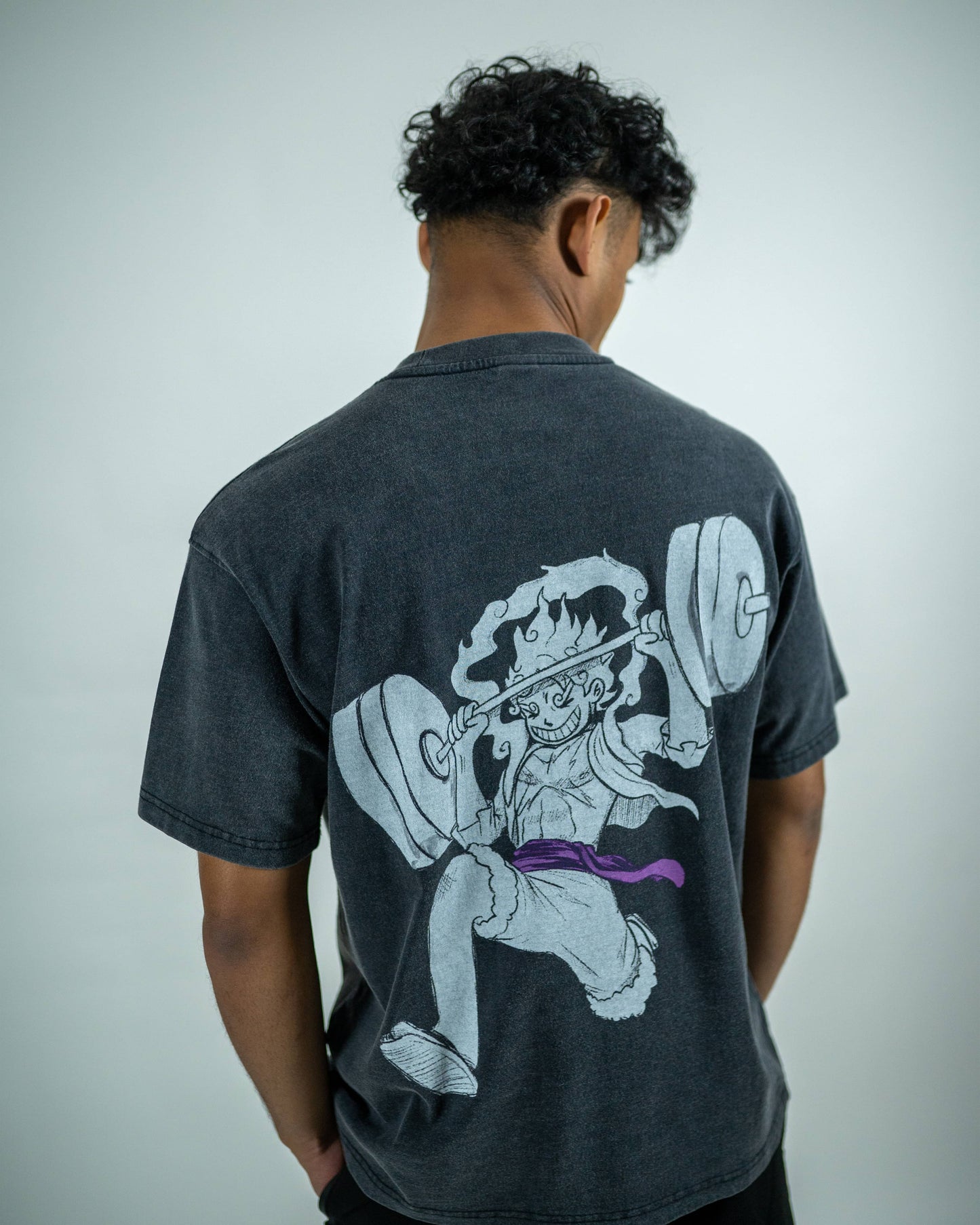 Back view of a model wearing a black Roki muki muki oversized t-shirt featuring a manga-inspired design