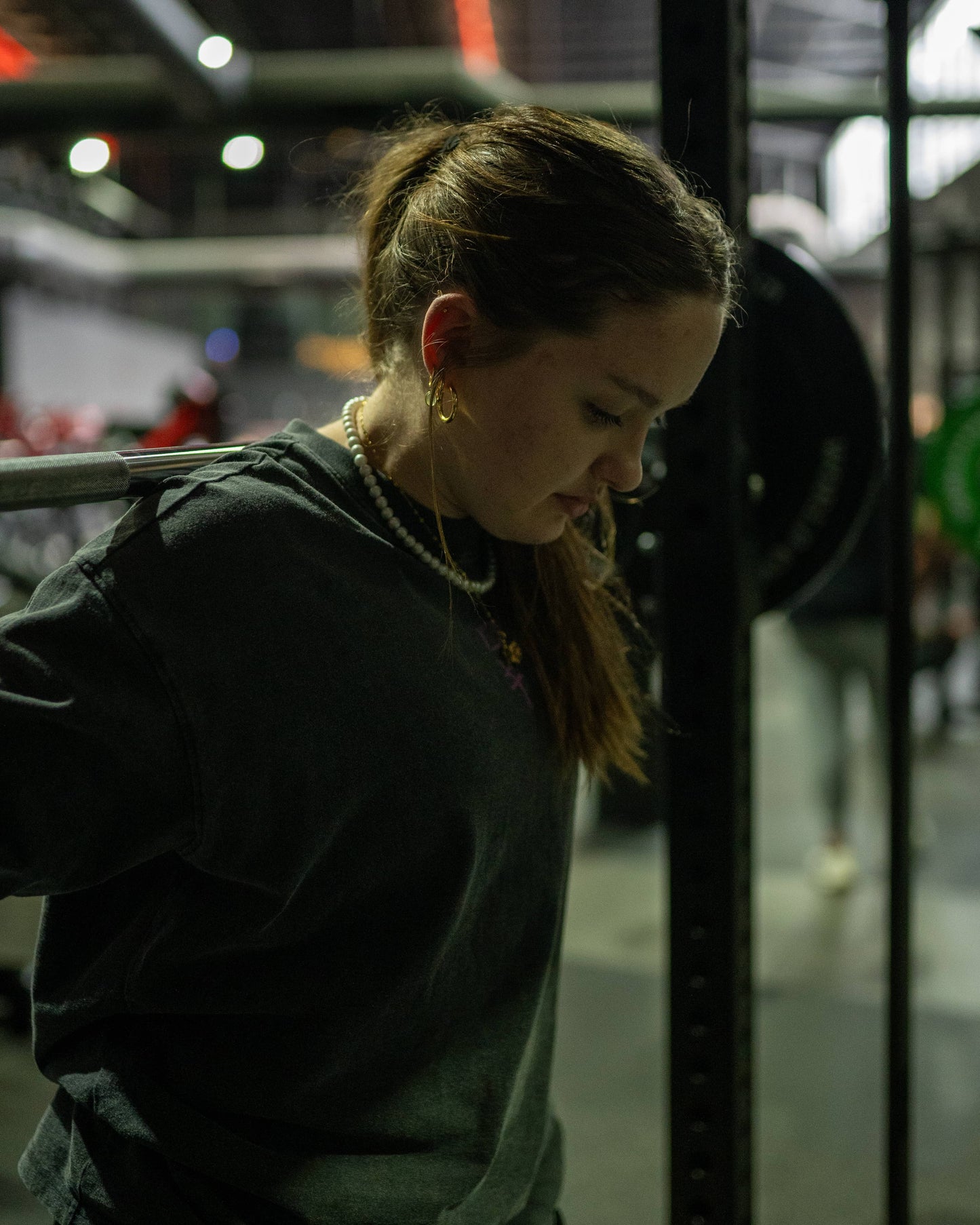 Diagonal view of a model wearing a black Roki muki muki oversized t-shirt in a gym squating