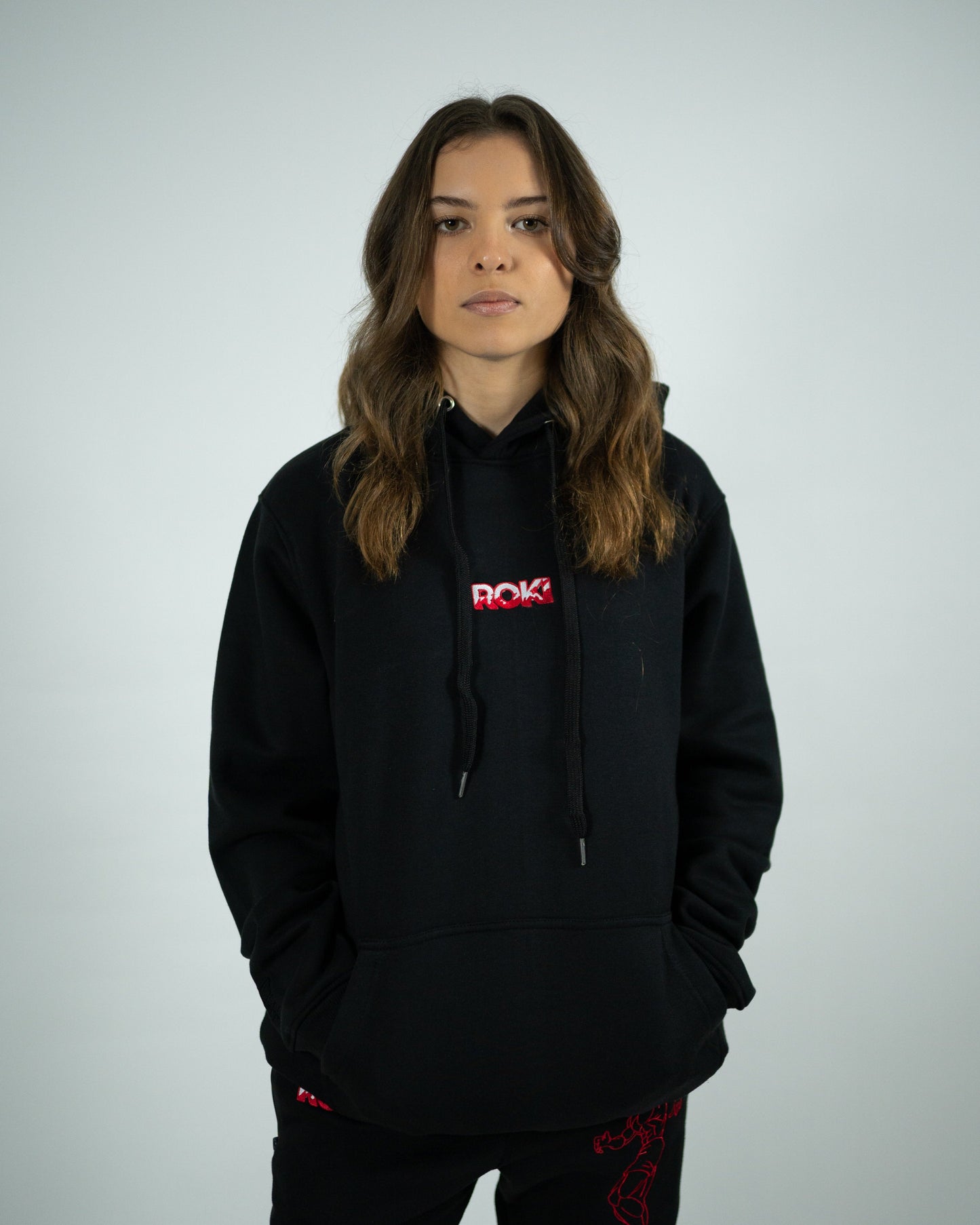 Female model wearing Sekai Saikyo Hoodie with red ROKI logo and relaxed pump-cover fit paired with demon back sweatpants