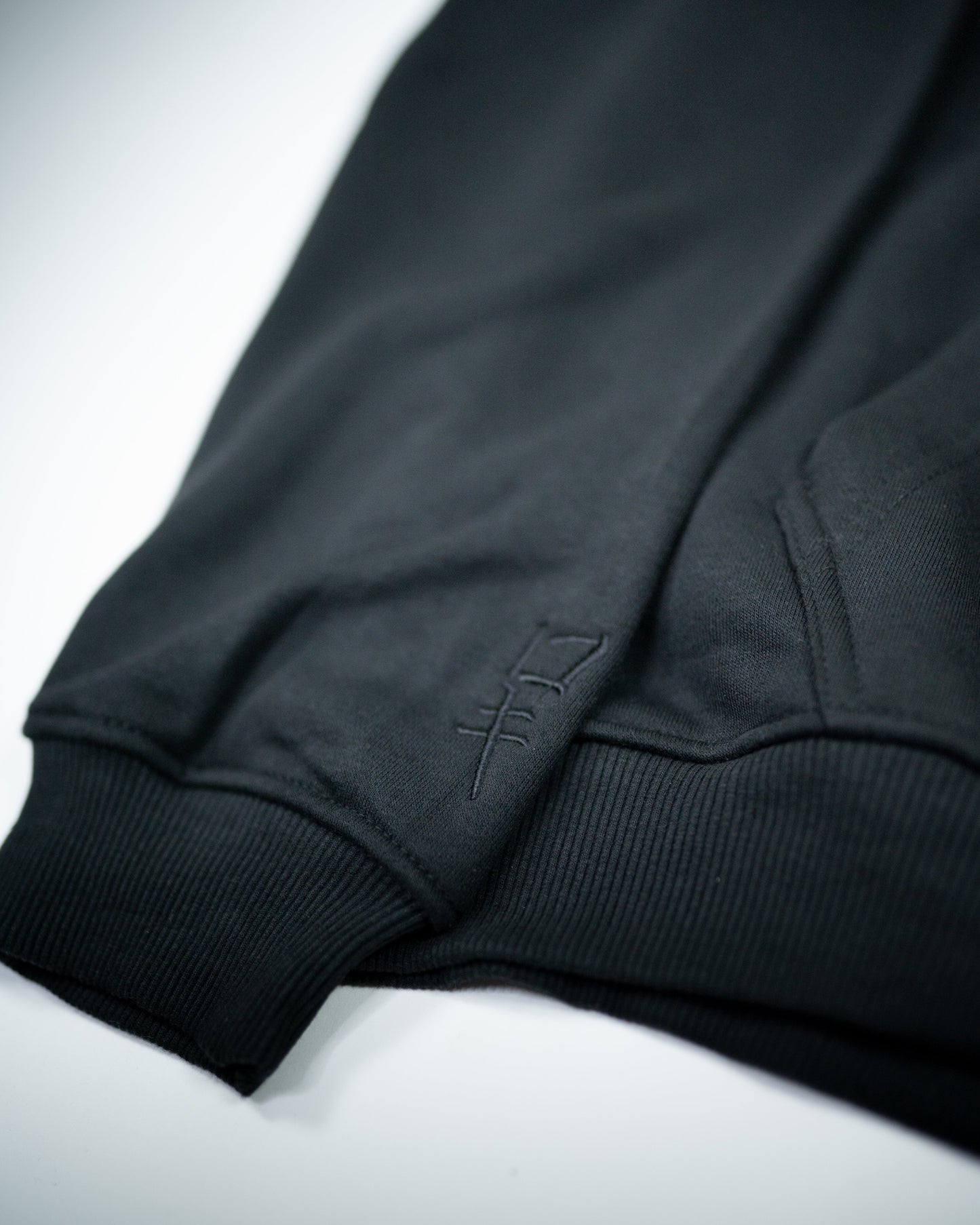 Close-up of Sekai Saikyo Hoodie sleeve cuff showing subtle black embroidered kanji near ribbed hem