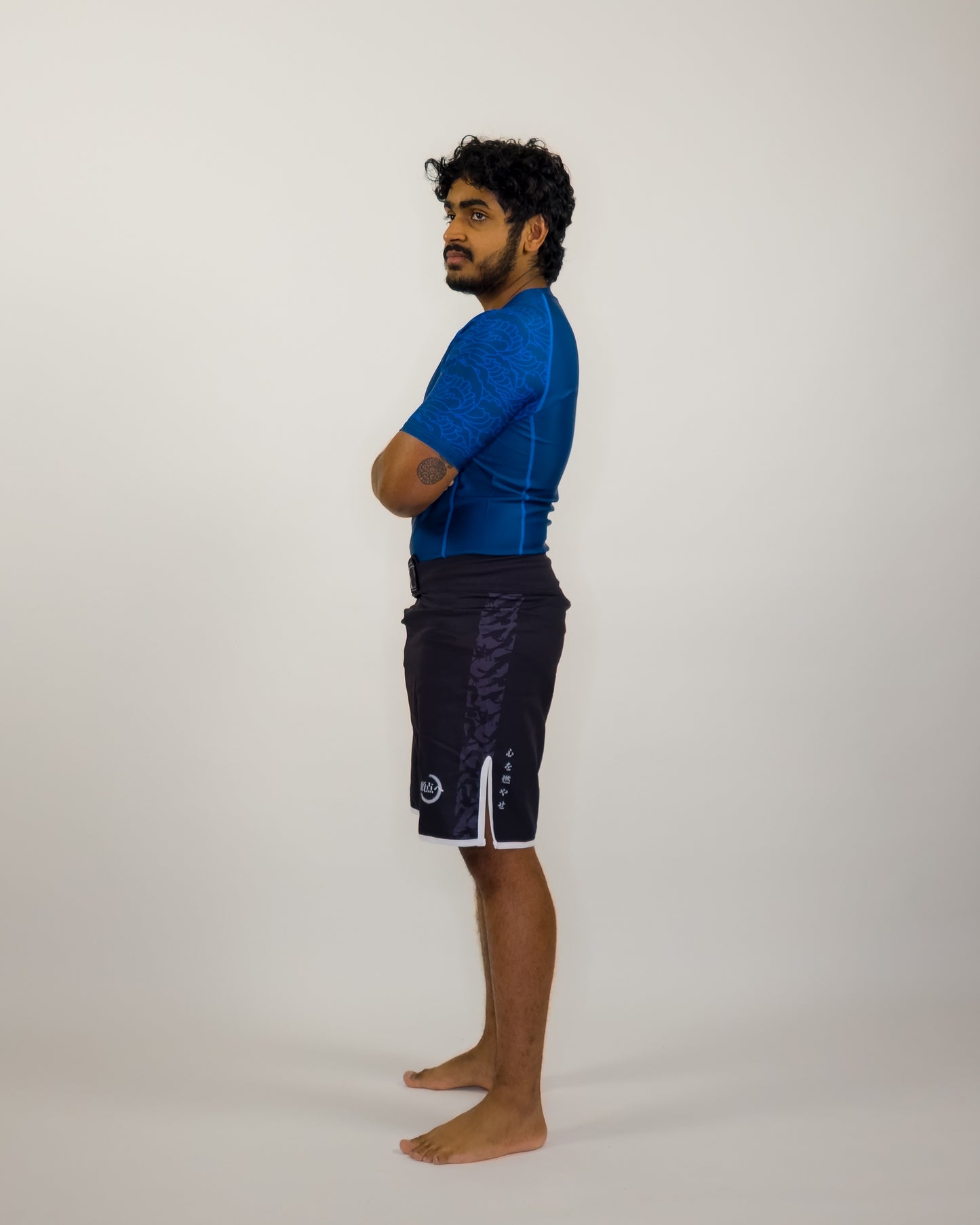 Man wearing a blue shirt and black shorts on a white background