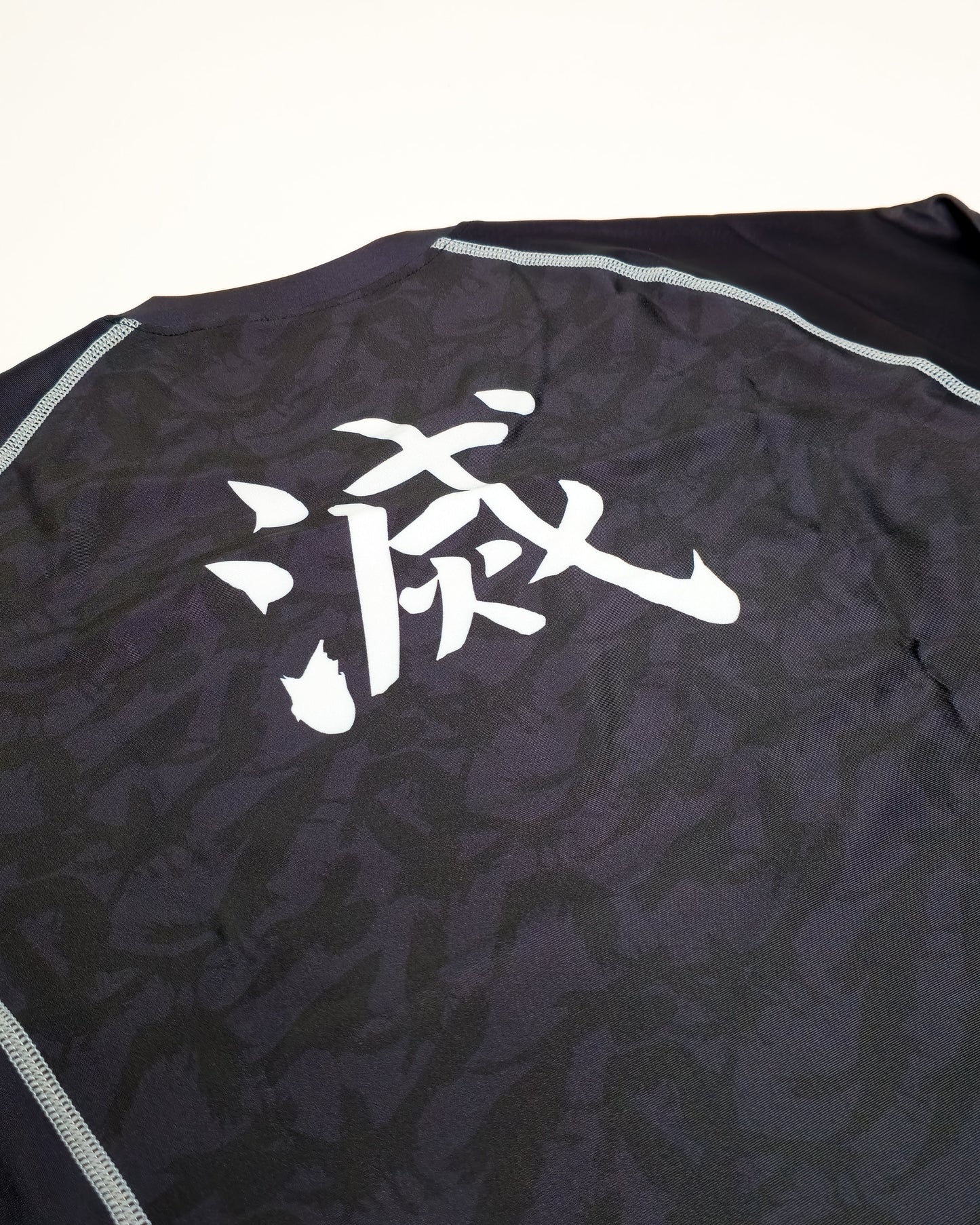 Black crow rash guard closeup with white text on a white background