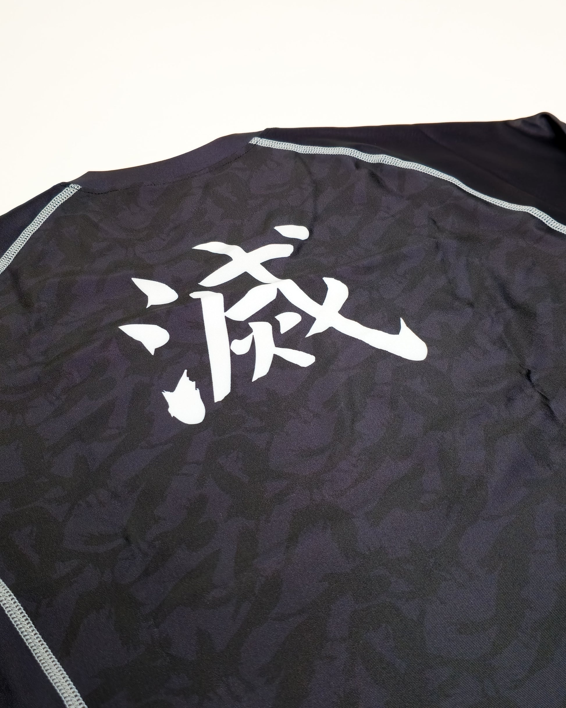 Black crow rash guard closeup with white text on a white background