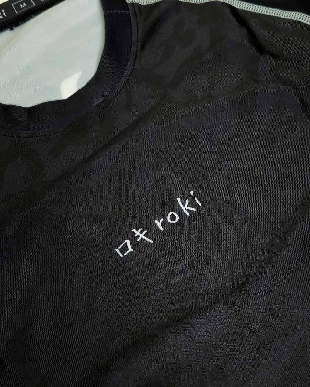 Black rash guard with 'roki' logo on a white background