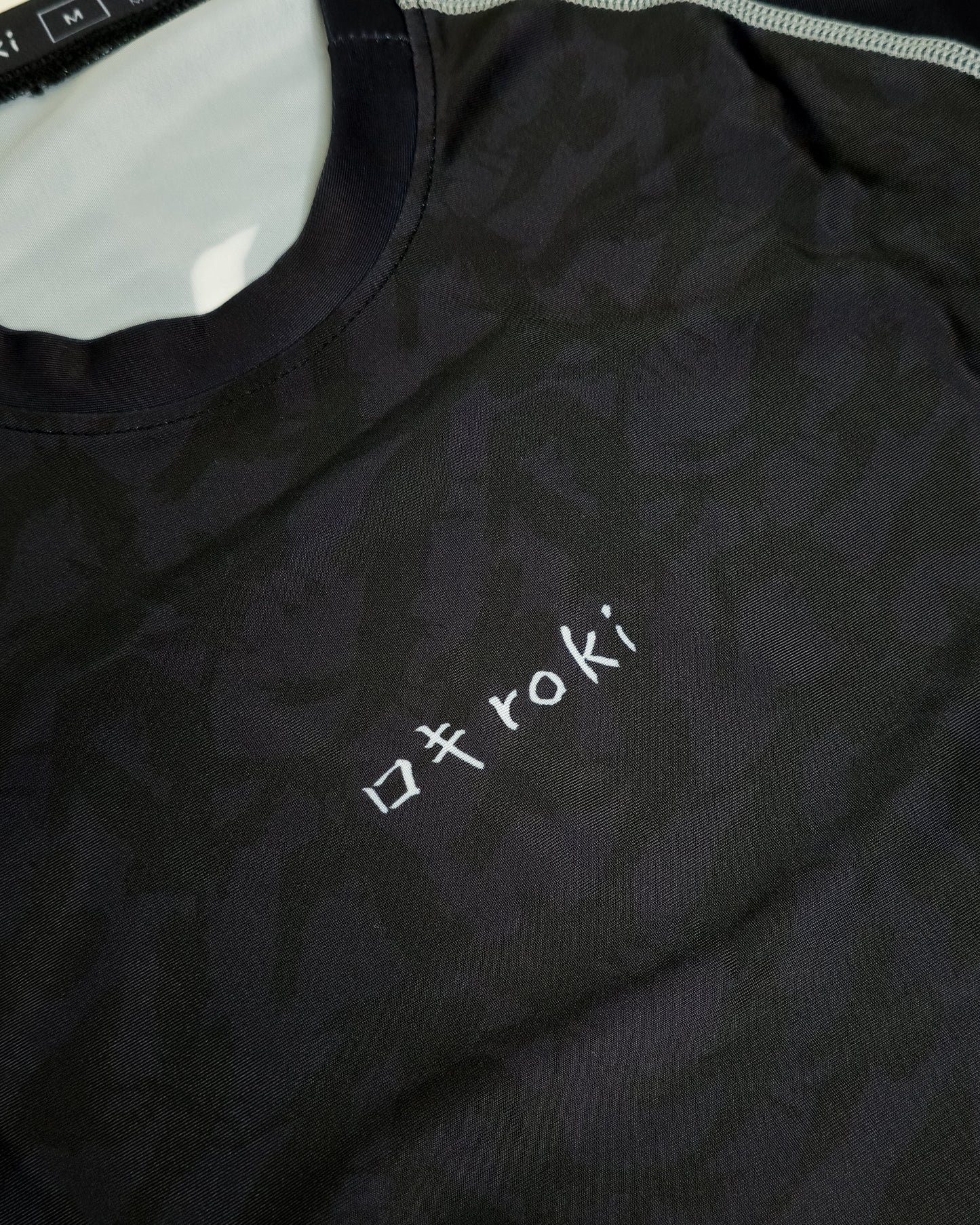 Black rash guard with 'roki' logo on a white background