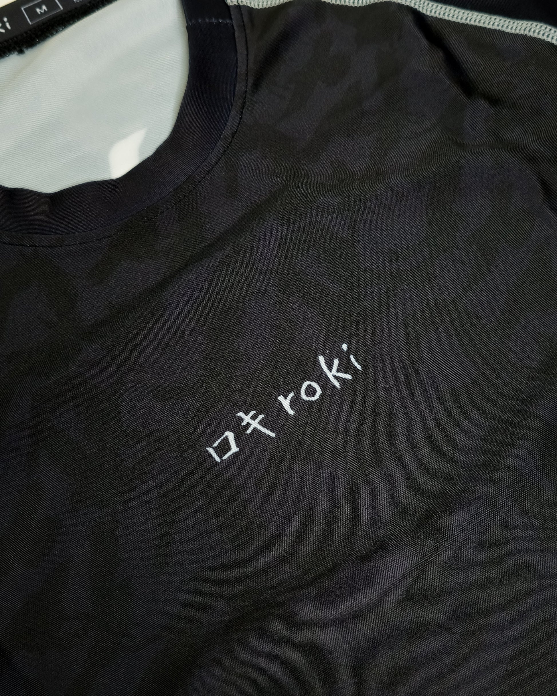Black rash guard with 'roki' logo on a white background