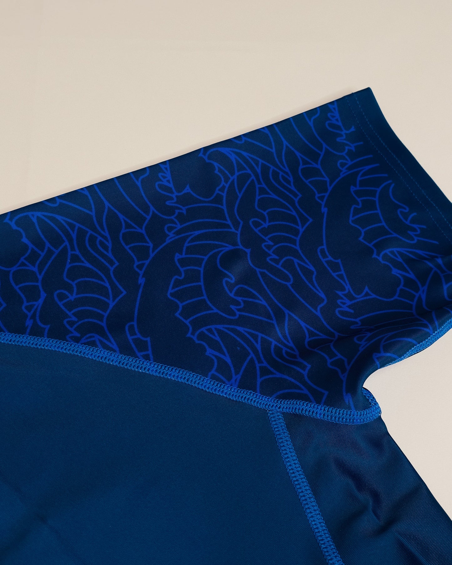 Blue rash guard with wave pattern on a white background, sleeve closeup