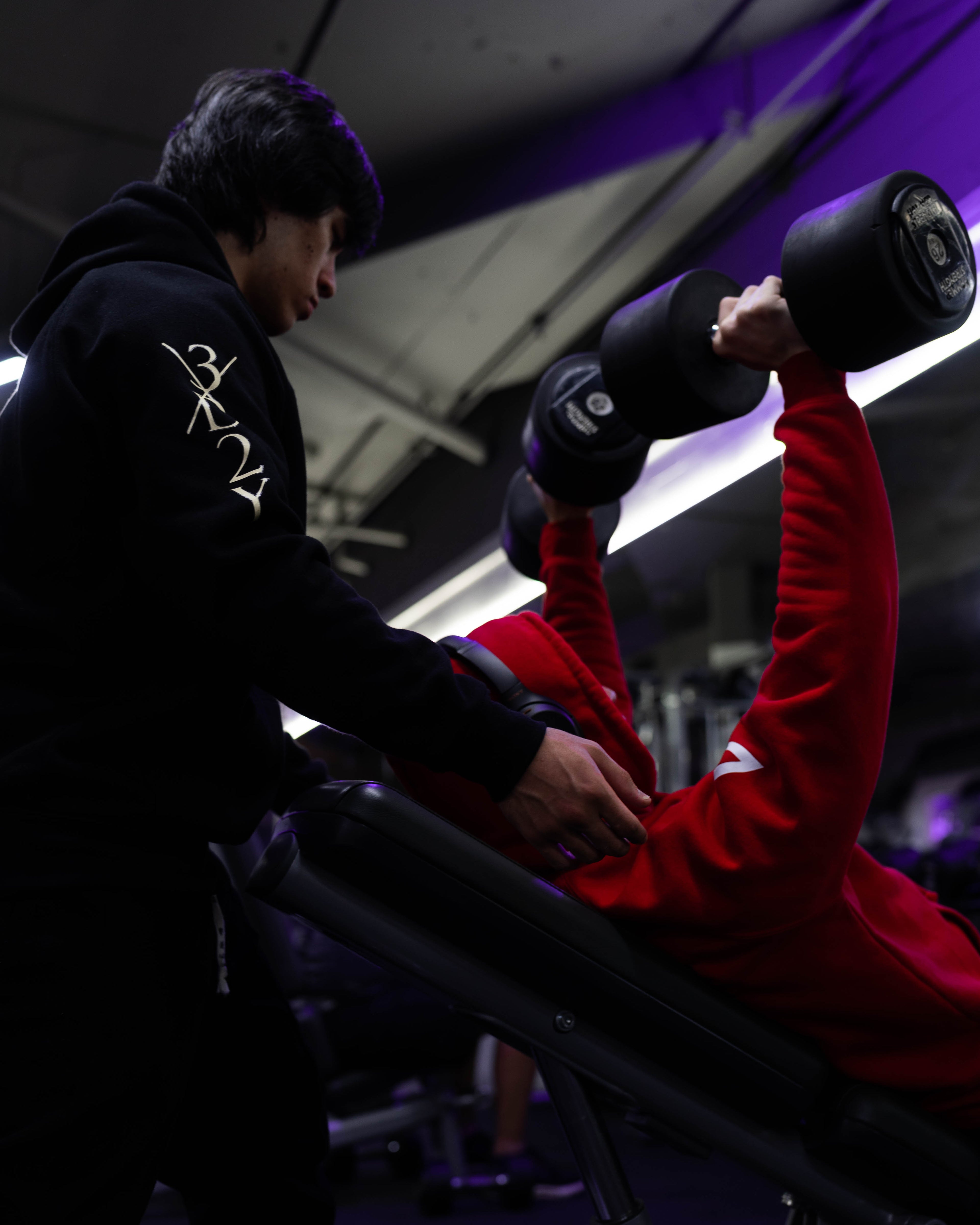 Man lifting dumbbells while wearing red anime hoodie