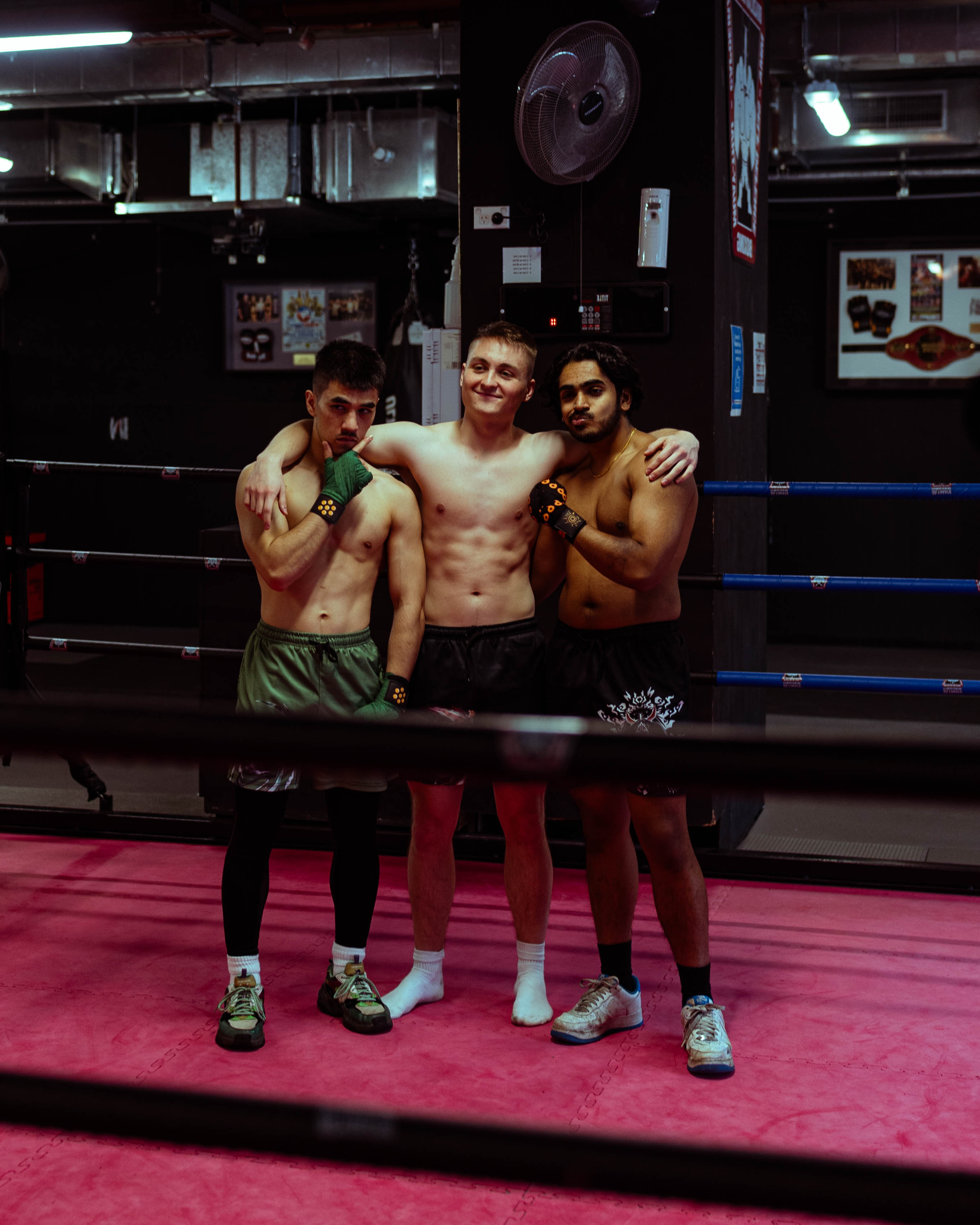 Three athletes standing in boxing ring wearing anime hand wraps and shorts