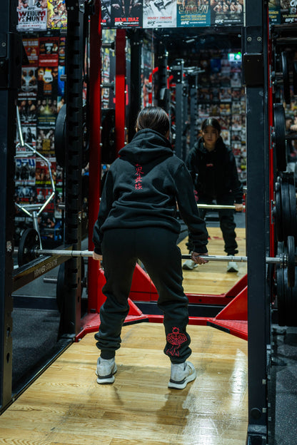 Female fighter lifting weights wearing Baki anime hoodie and joggers