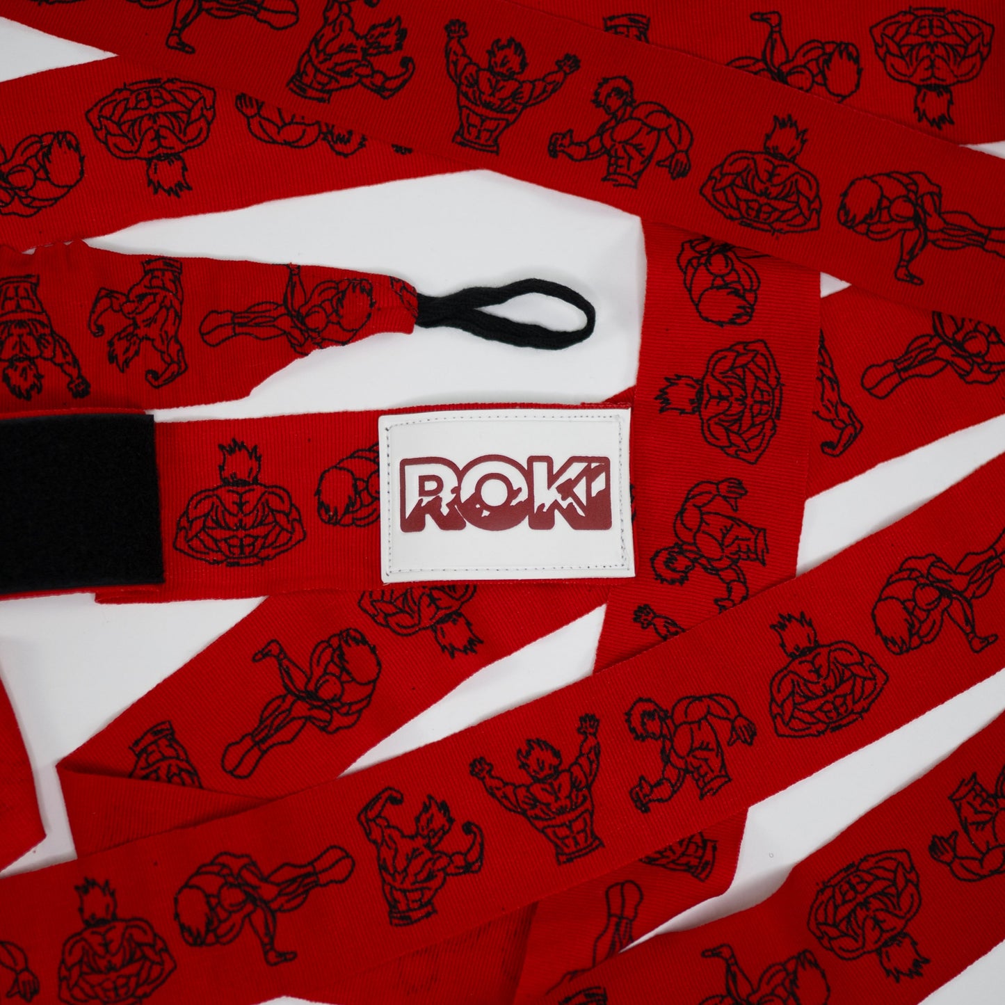 red anime-themed boxing hand wraps with muscular figure illustrations and white roki patch, rolled out flat with thumb loop