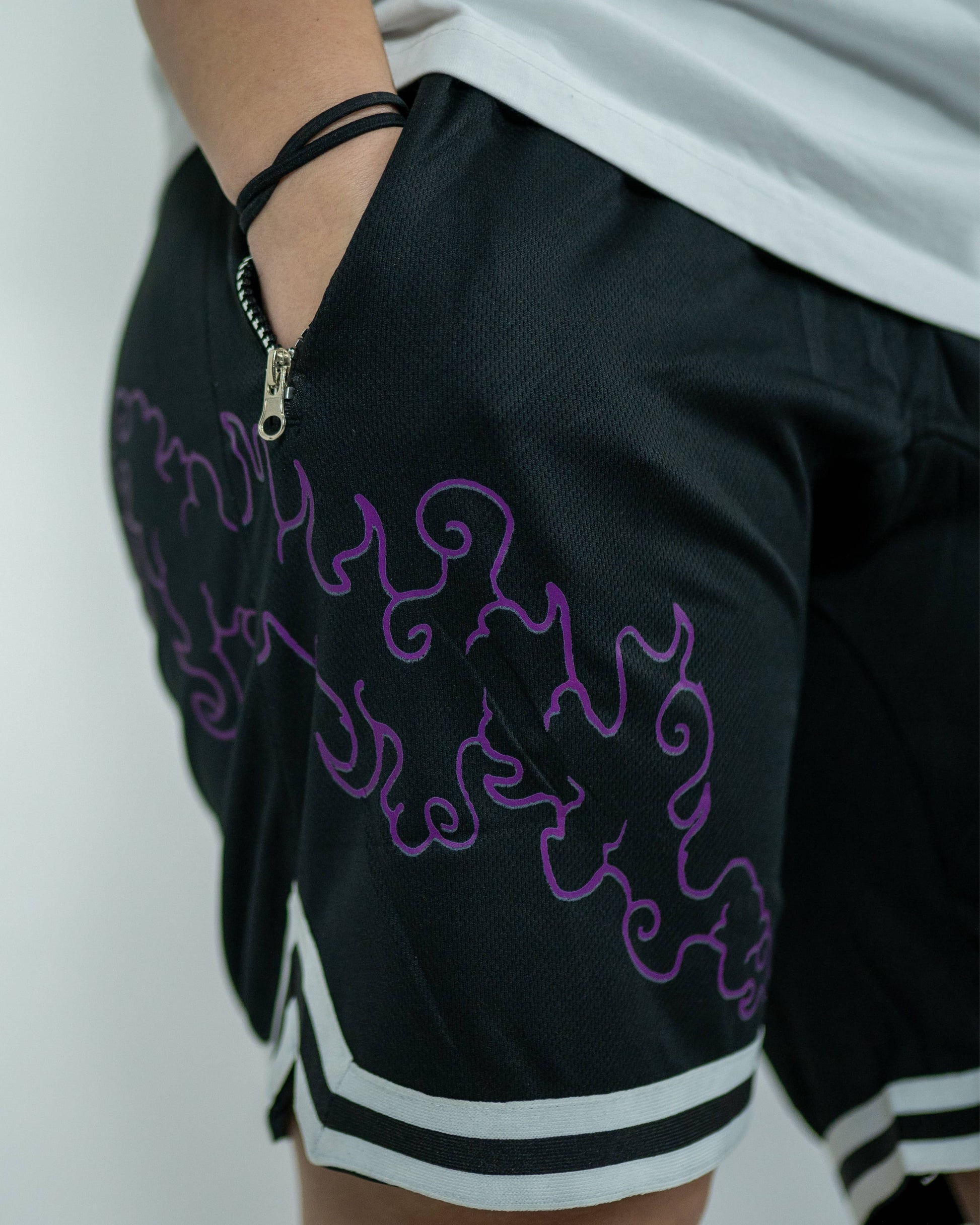 Side close-up of a model wearing black Roki Awakened gym shorts featuring purple accents and Roki logo