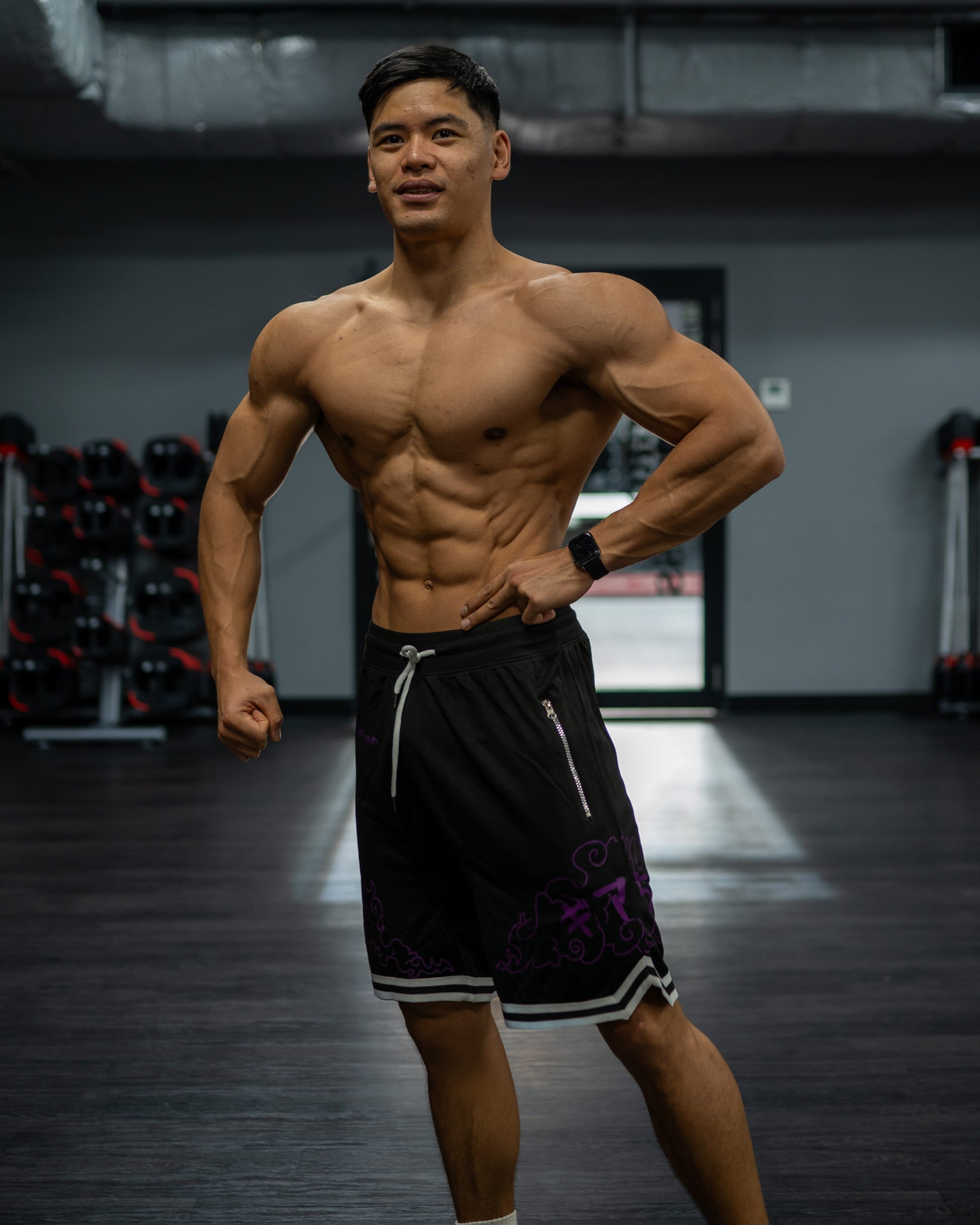Front view of a shredded model wearing black Roki Awakened gym shorts