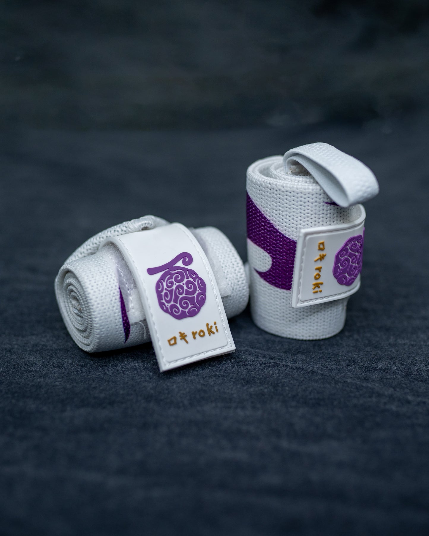 Close-up of white Roki Liberation wrist wraps with purple accents and gold Roki logo