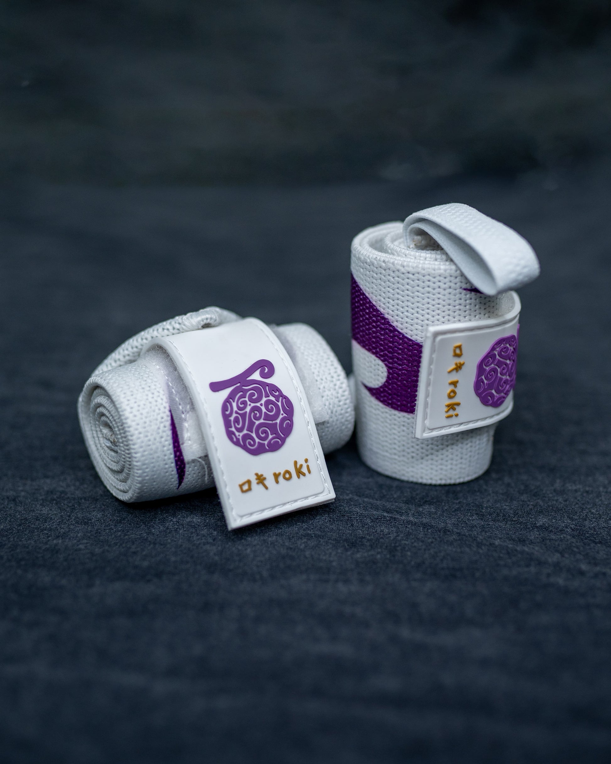 Close-up of white Roki Liberation wrist wraps with purple accents and gold Roki logo