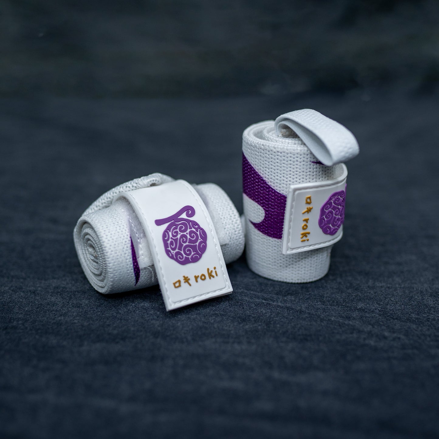 Close-up of white Roki Liberation wrist wraps with purple accents and gold Roki logo