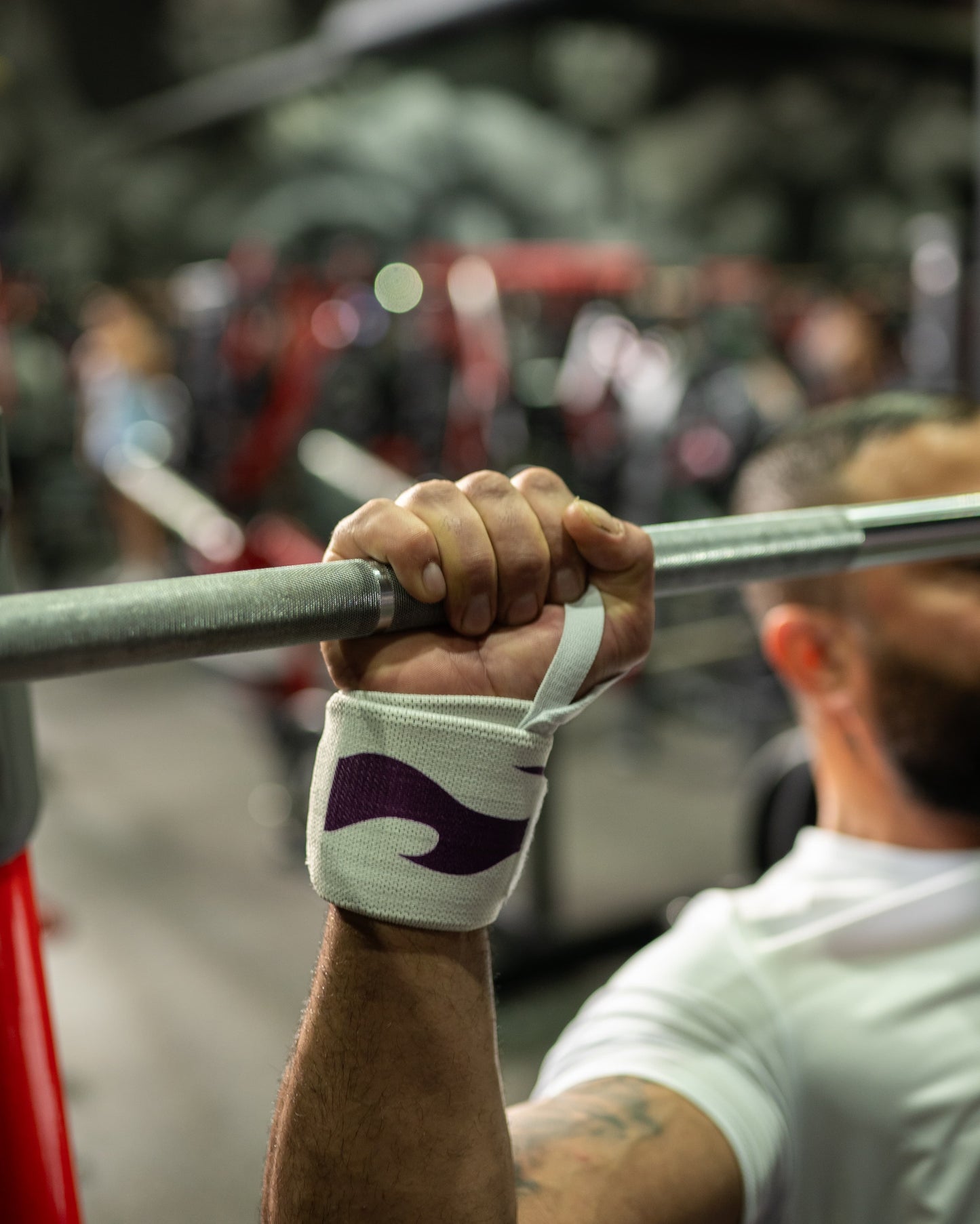 Close-up of a model wearing Roki Liberation wrist wraps lifting a barbell in a gym