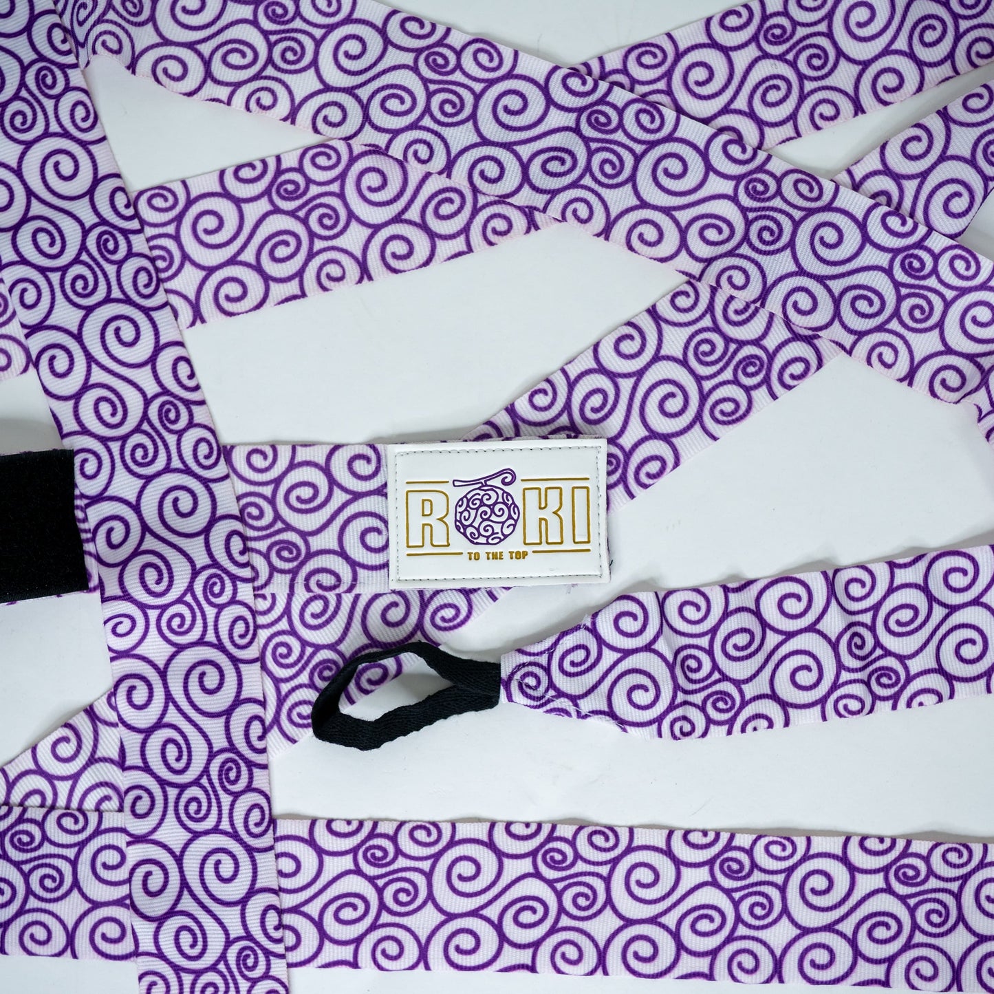 Roki gomu hand wraps laid out, featuring purple accents, roki logo, thumb-loop and velcro patch
