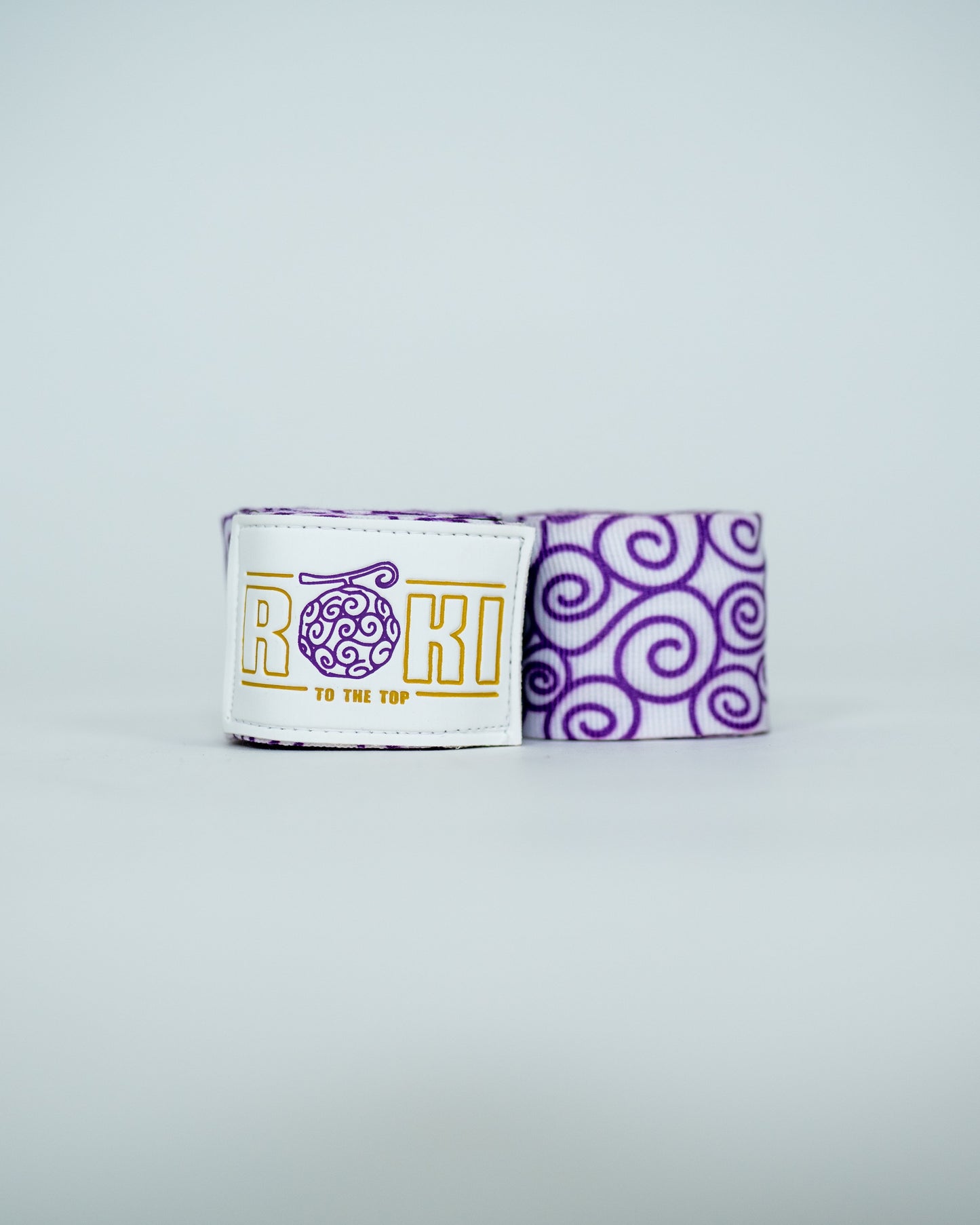 Roki gomu hand wraps rolled up, featuring purple accents, roki logo, thumb-loop and velcro patch