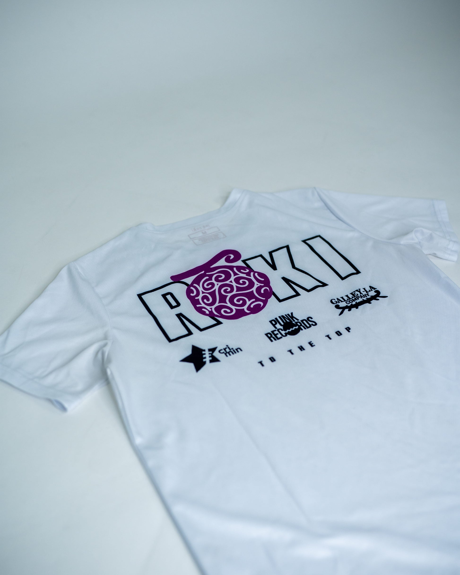 Back view of a white Roki Liberation training shirt featuring anime-inspired sponsor logos