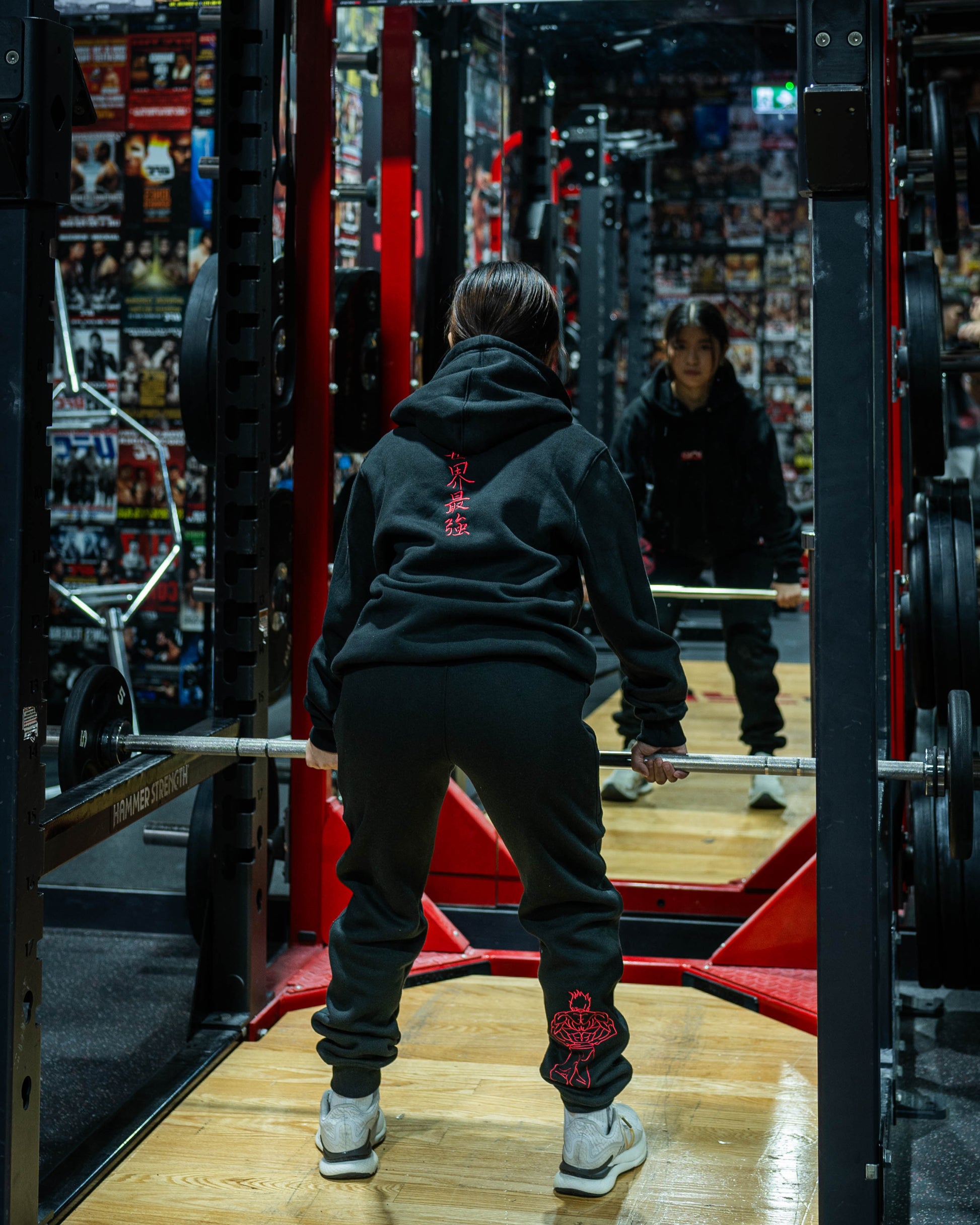 Model deadlifting in gym wearing Grappler Joggers and Sekai Saikyo Hoodie with matching red demon back embroidery