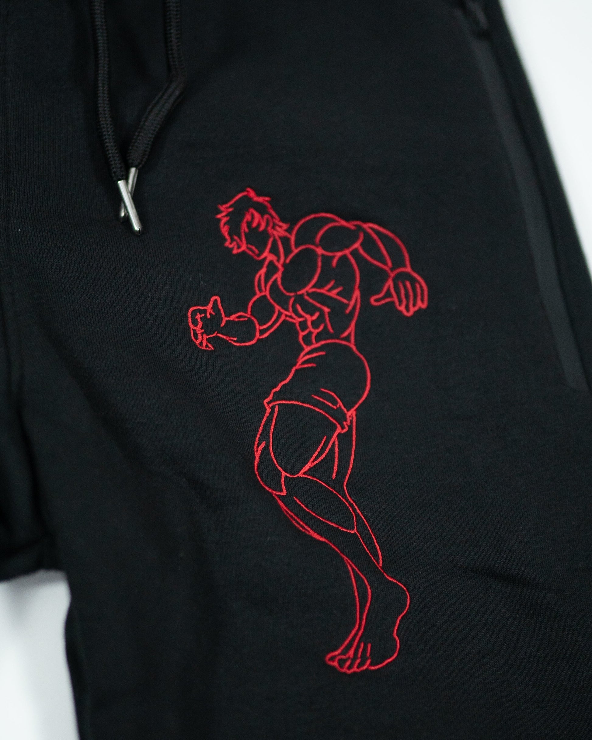 Close-up of Grappler Joggers showing red demon back character embroidery detail on black cotton fabric