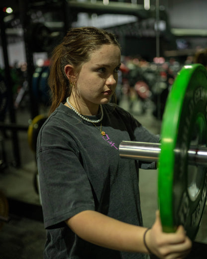 Front view of a model wearing a black Roki muki muki oversized t-shirt in a gym handling plates