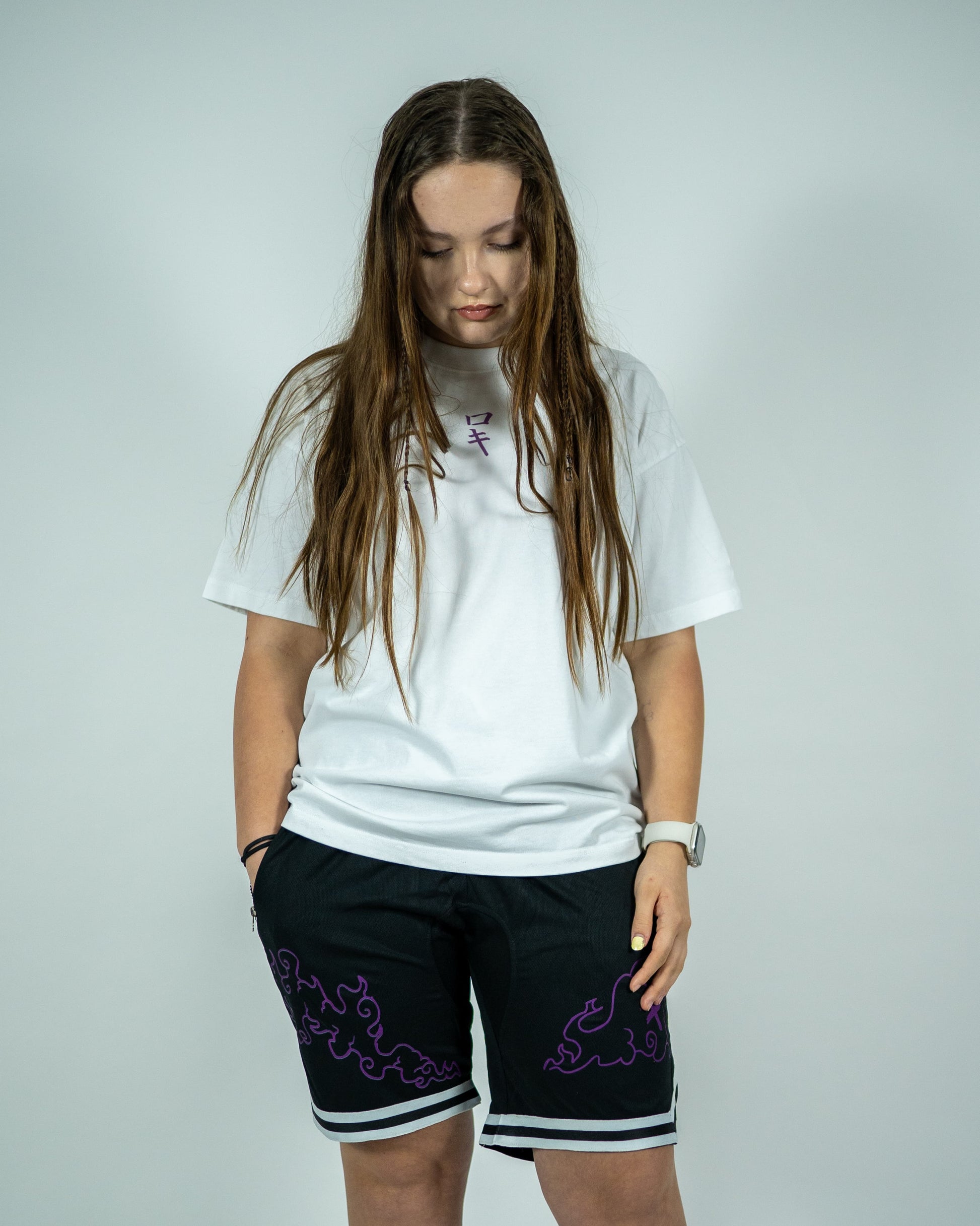 Front view of a model wearing a white Roki muki muki oversized t-shirt featuring a purple Roki logo