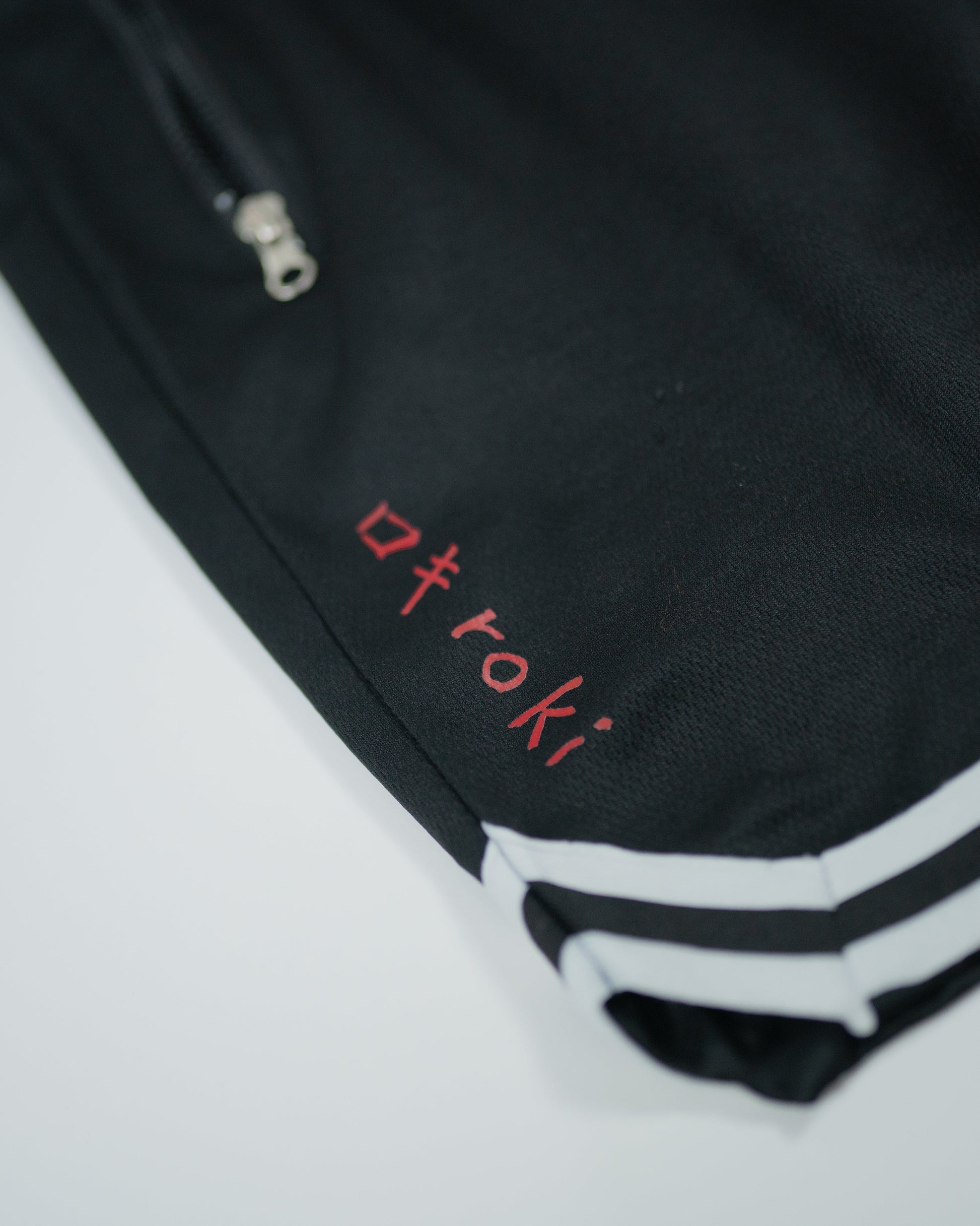 Angled close-up of Roki Gym Shorts with red logo print and white striped hem