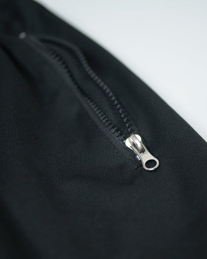 Macro close-up of zippered pocket on black Roki Gym Shorts showing stitching and fabric texture