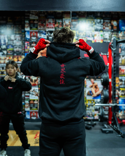 Gym setting shot of Sekai Saikyo Hoodie showing oversized pump-cover fit and red kanji embroidery on back
