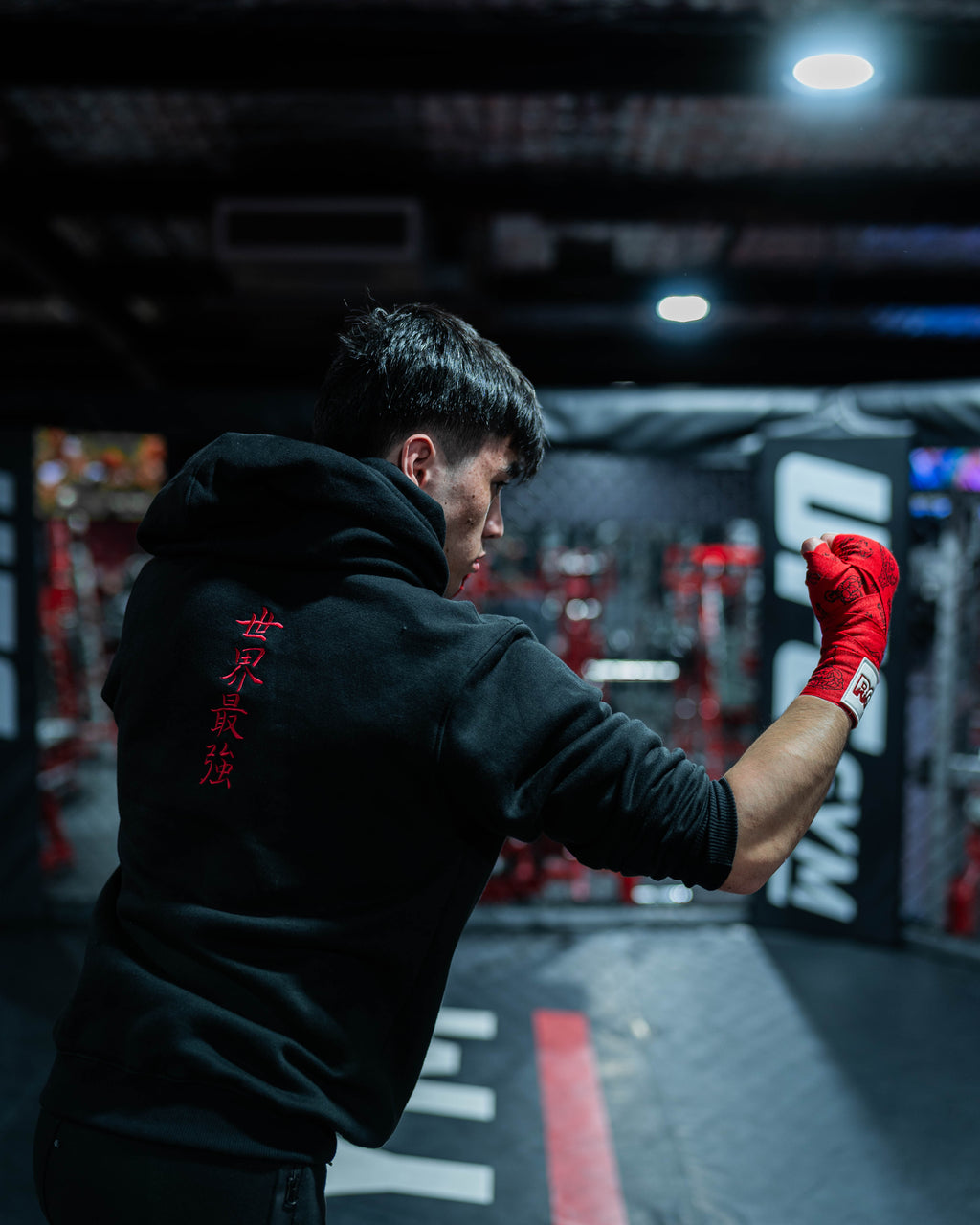 Fighter wearing Sekai Saikyo Hoodie in cage showing red kanji embroidery on back during shadowboxing