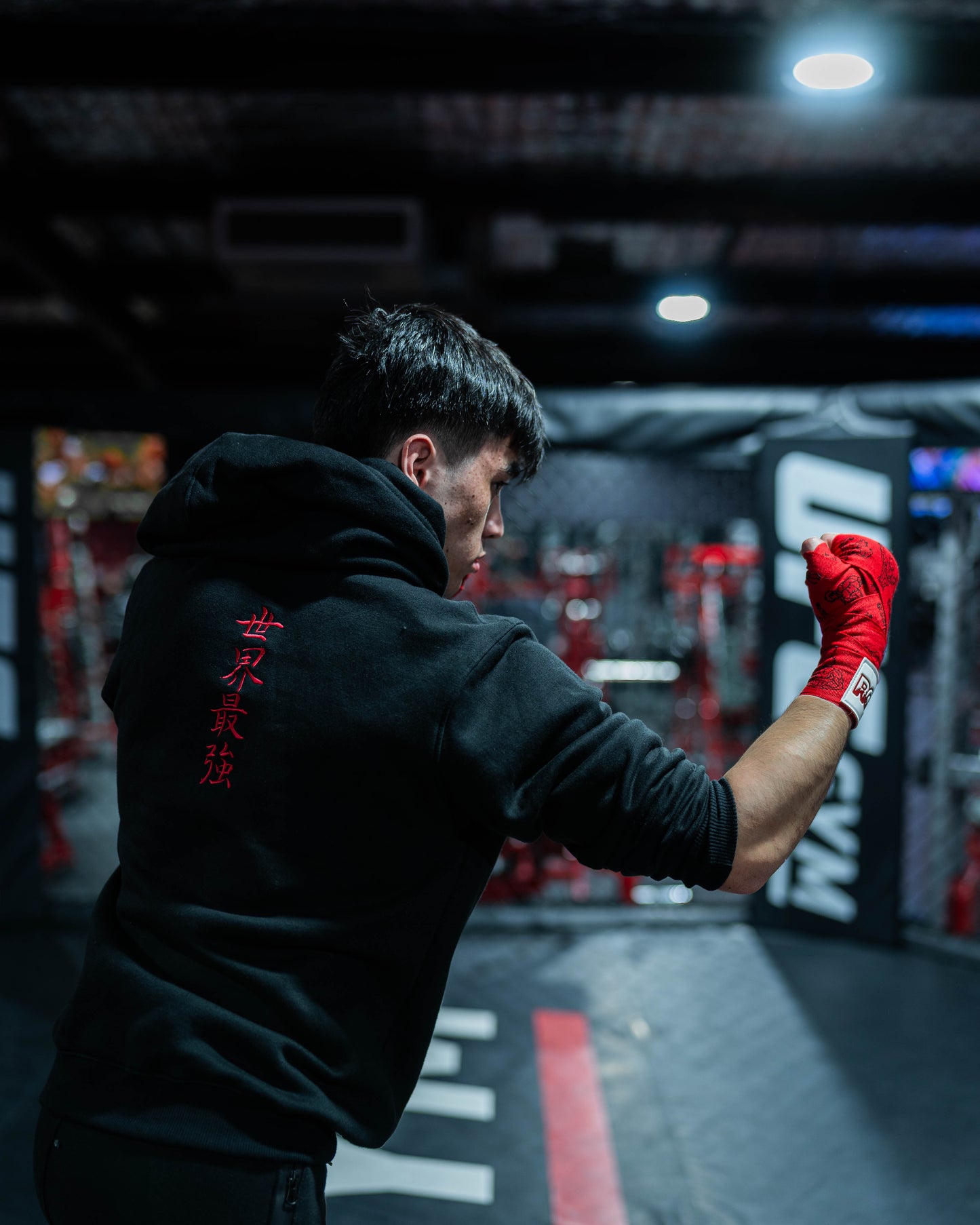 Fighter wearing Sekai Saikyo Hoodie in cage showing red kanji embroidery on back during shadowboxing