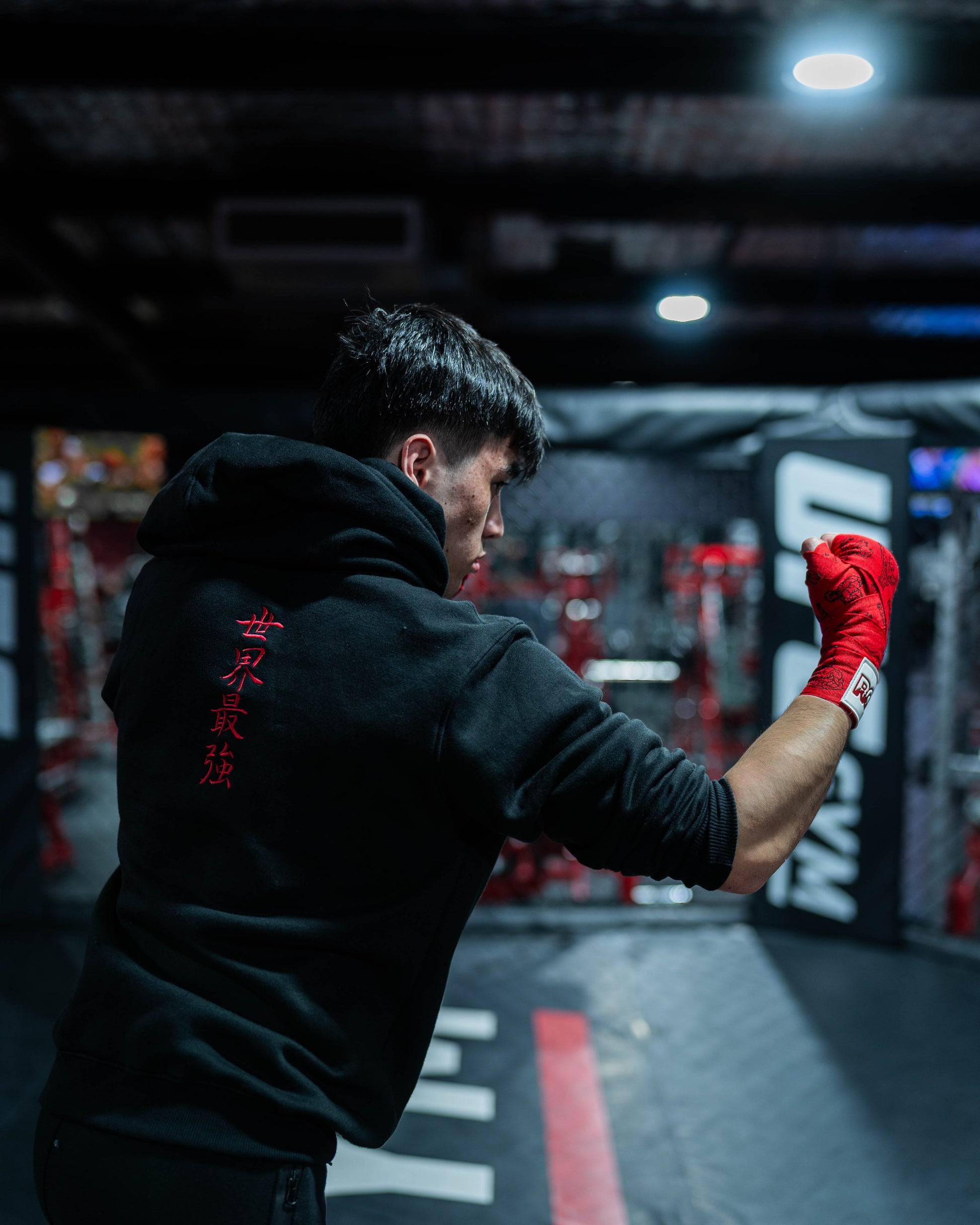 Fighter wearing Sekai Saikyo Hoodie in cage showing red kanji embroidery on back during shadowboxing