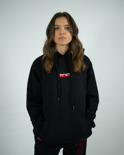 Female model wearing Sekai Saikyo Hoodie with red ROKI logo and relaxed pump-cover fit paired with demon back sweatpants